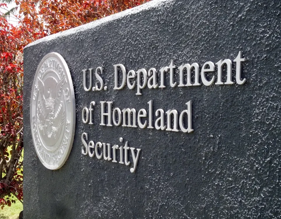 Image of US Department of Homeland Security (DHS) Seal on Sign Outside of Federal Building.